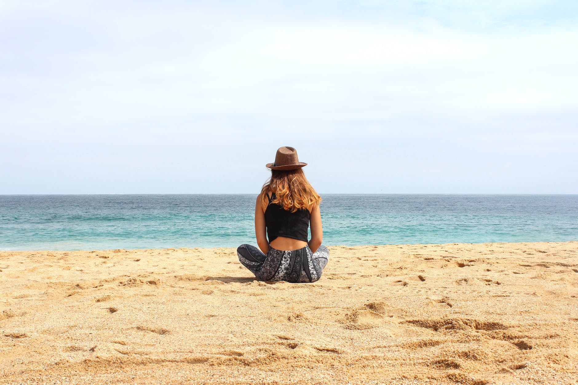 woman sitting on seashore at daytime